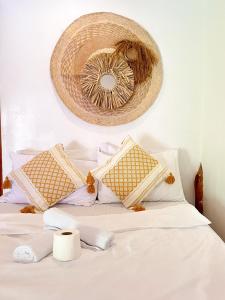 a bed with white sheets and pillows and a basket on the wall at KnowWell Siargao Nâked in General Luna