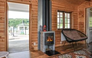 a fireplace in a wooden room with a chair at Lovely home in Ringstad in Kil