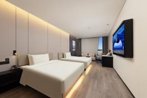 una camera d'albergo con due letti e una TV a schermo piatto di Atour Hotel Tianjin Binhai Yujiapu Financial District a Tianjin