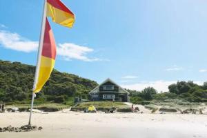 un drapeau sur la plage avec une maison en arrière-plan dans l'établissement Seabreeze at One Mile, à Boat Harbour