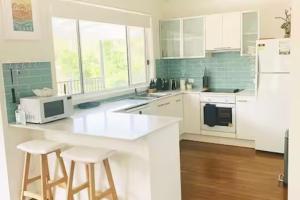 une cuisine avec des armoires blanches et un comptoir avec des tabourets dans l'établissement Seabreeze at One Mile, à Boat Harbour 22 autres photos