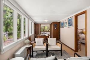 a living room with white chairs and windows at Glendarra in Point Lonsdale