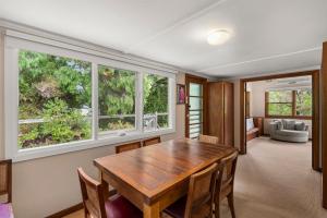a dining room with a wooden table and two windows at Glendarra in Point Lonsdale +5 photos