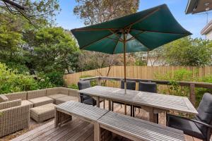 a wooden table with a green umbrella on a patio at Glendarra in Point Lonsdale