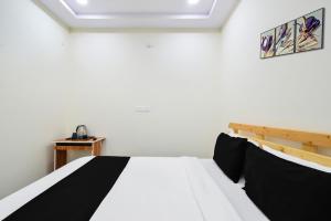a bedroom with a bed with black and white sheets at Super Collection O Adibatla Hyderabad in Ibrāhīmpatan +26 photos