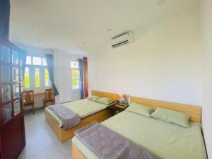 a hotel room with two beds and a table at Green Homestay Tuy Hòa in Liên Trì (4)