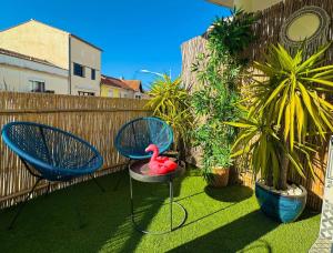 勒格罗-迪鲁瓦Suites Aronas-hébergements climatisés rive droite plein centre ville的天井配有两把椅子和一碗粉红色鸭子