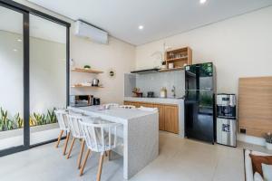 a kitchen with a table and chairs and a refrigerator at Jobon Villas by Great Bali Villas in Uluwatu