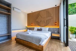 a bedroom with a bed and a wooden wall at Jobon Villas by Great Bali Villas in Uluwatu +80 photos