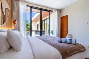 a bedroom with a large bed and a large window at Jobon Villas by Great Bali Villas in Uluwatu