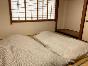 a unmade bed in a room with a window at Seven House Family room in Kurume