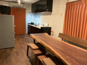 a kitchen with a wooden table and a refrigerator at Seven House Family room in Kurume