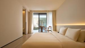 una camera da letto con un grande letto bianco e un tavolo di 西塘光向度艺术酒店WNDR Hotel Xitang a Jiaxing