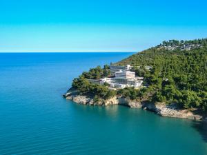 une île dans l'eau avec un grand bâtiment dans l'établissement Pugnochiuso Resort Hotel del Faro, à Vieste