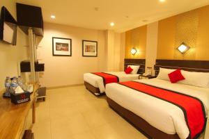 a hotel room with two beds and a television at Citi M Hotel Gambir in Jakarta