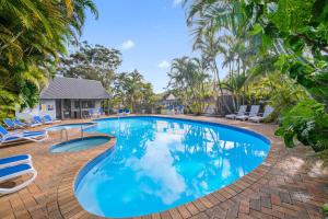 a large swimming pool with chairs and trees at Shores Beach & Lakeside Villas in Elizabeth Beach