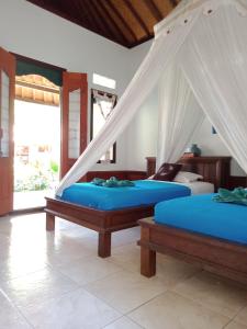 two beds in a room with blue sheets at Reef Seen Divers' Resort in Pemuteran