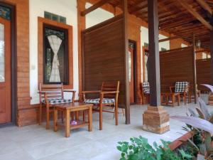 a porch with wooden chairs and a table at Reef Seen Divers' Resort in Pemuteran