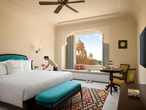 a woman in a hotel room with a bed and a window at Storii By ITC Hotels, Jaisalmer in Jaisalmer