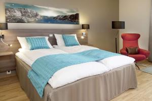 a bedroom with a large bed and a red chair at Scandic Stavanger Airport in Sola