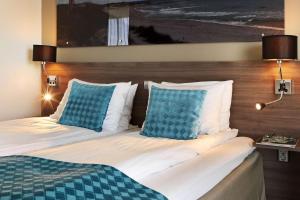 a hotel room with a bed with blue pillows at Scandic Stavanger Airport in Sola