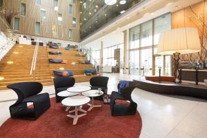 a lobby with tables and chairs and a staircase at Scandic Stavanger Airport in Sola