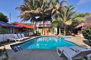 una piscina con sillas y palmeras frente a una casa en Hosteria Canoa en Canoa