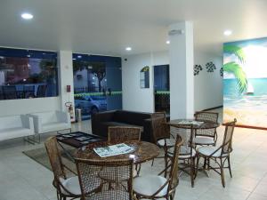 sala de estar con mesas, sillas y sofá en Coqueiros Express Hotel, en Maceió
