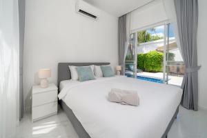 a white bedroom with a large bed and a window at The Greens Phuket Villa with swimming pool 18 in Ban Saiyuan (1) +32 photos