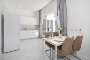 a white dining room with a white table and chairs at The Greens Phuket Villa with swimming pool 18 in Ban Saiyuan (1)