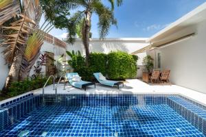 a swimming pool with two blue chairs and a house at The Greens Phuket Villa with swimming pool 18 in Ban Saiyuan (1)