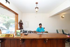 a man sitting at a desk in an office at Lazo Golden Valley Resort , Munnar in Munnar