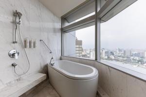 a bathroom with a bath tub and a window at Bangkok Marriott Hotel Sukhumvit in Bangkok