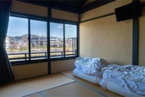 a room with two beds and a large window at Kyoto Machiya inn offering scenic Kamo River views in Kyōto