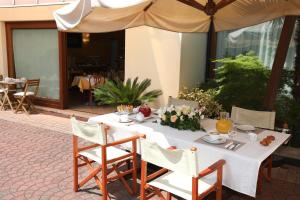 ein weißer Tisch mit Stühlen und einem Sonnenschirm in der Unterkunft Hotel Cris in Mestre + 26 Fotos