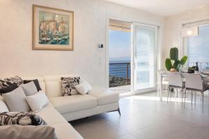 a living room with a white couch and a table with chairs at Terrace of Wally - Apartment With Pool in Torri del Benaco