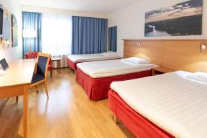 a hotel room with three beds and a desk at Scandic Kouvola in Kouvola +55 photos