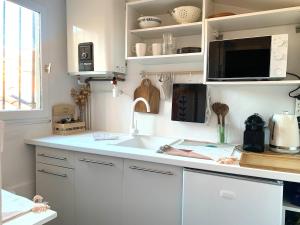 a kitchen with white cabinets and a sink and a microwave at Studio in historical monument in city center in Montpellier