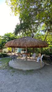 a large straw umbrella with chairs and a table at ELEN INN - Malapascua Island FAN ROOM #1 in Malapascua Island +20 photos
