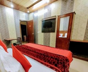 齐拉克普尔Hotel Grand的卧室里有一张床，床上铺着一条红毯子