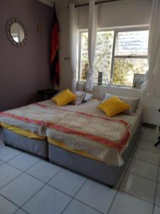 a bedroom with a large bed with yellow pillows at 120 steps to the beach in Pringle Bay