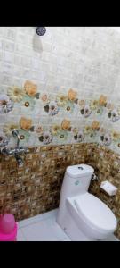 a bathroom with a toilet and a floral shower curtain at Beauty Guest House in Bodh Gaya +23 photos