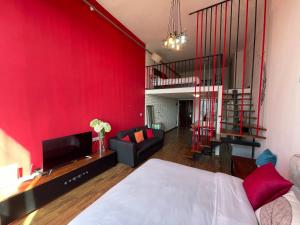 a bedroom with a red wall and a living room at April Fair Duplex Apartment Guagnzhou South Railway Station Min Jie Branch in Guangzhou