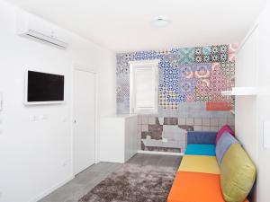 a room with a colorful couch and a tile wall at Stay COOPER l Guesthouse 37 in Bolzano