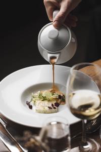 a person is pouring sauce into a plate of food at Marholmen in Norrtälje