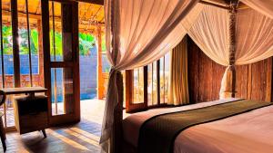 a bedroom with a bed with a canopy and windows at Pradnya Villa in Ubud +93 photos