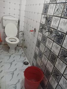 a bathroom with a toilet and a red bucket at Sunbeam Stay in Prayagraj
