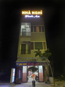 a tall yellow building with a neon sign on it at Nhà Nghĩ Bà Rịa - Bình An in Ấp Nam