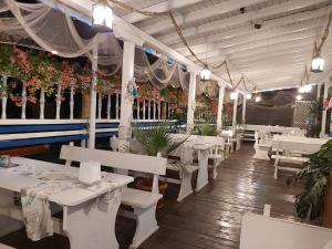 a restaurant with white tables and benches and plants at Hotel North in Primorsko