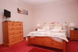 a bedroom with a bed with a dresser and a tv at Shiant View in Lochs
